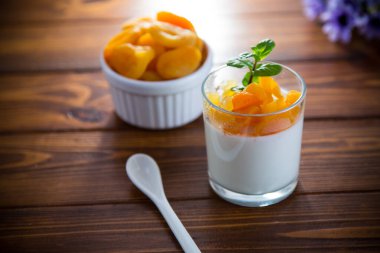 Açık meyveli yoğurt ve koyu ahşap masada kurutulmuş kayısı..