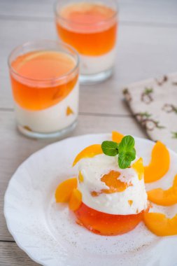 Ahşap bir masada reçelli, kremalı ve taze naneli meyve tatlısı..