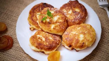 Kurutulmuş kayısılı süzme peynir krepleri ve ahşap bir masada bal.