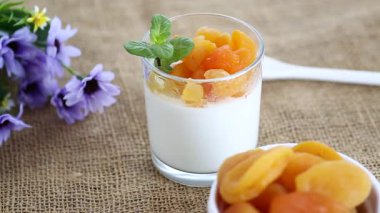 Açık meyveli yoğurt ve koyu ahşap masada kurutulmuş kayısı..