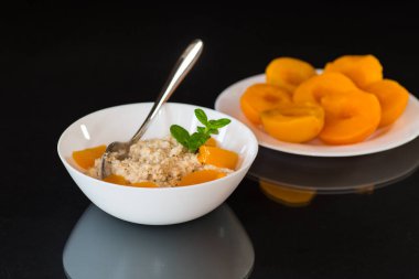 Sağlıklı kahvaltı, yulaf ezmesi, şeftali ve taze nane, siyah arka planda izole edilmiş..