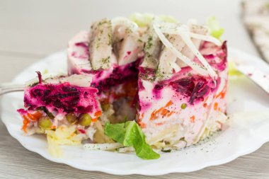 Ahşap bir masada pancar ve ringa balıklı katmanlı sebze salatası..