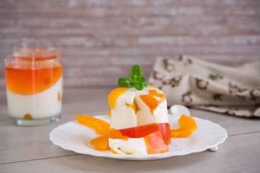 Ahşap bir masada reçelli, kremalı ve taze naneli meyve tatlısı..