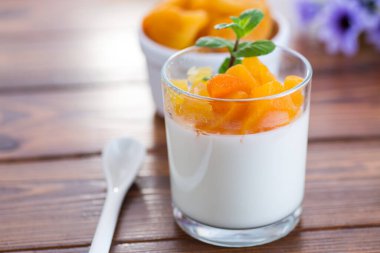 Açık meyveli yoğurt ve koyu ahşap masada kurutulmuş kayısı..