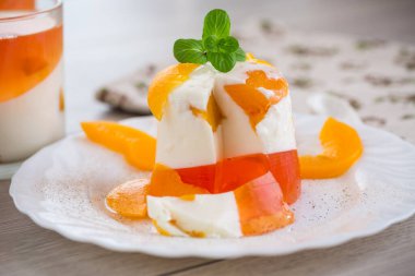 Ahşap bir masada reçelli, kremalı ve taze naneli meyve tatlısı..