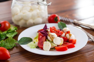 Taze sebzeler ve mozarella peyniri. Koyu ahşap bir masada bir tabakta..