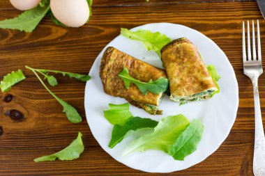 Beyaz bir tabakta yeşil ve roka ile iştah açıcı omlet..