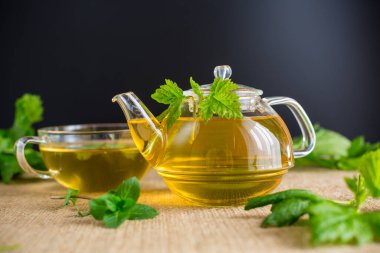 Bitki çaydanlığı ve siyah arka planda bir fincan çay..