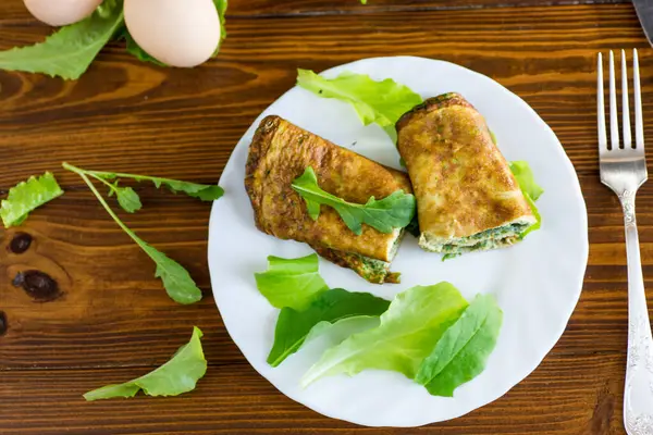 Beyaz bir tabakta yeşil ve roka ile iştah açıcı omlet..