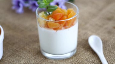 Açık meyveli yoğurt ve koyu ahşap masada kurutulmuş kayısı..