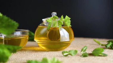 Frenk üzümü yapraklı yeşil çay ve cam çaydanlıkta nane ve siyah arka planda fincan..