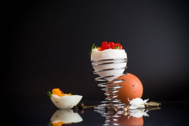 Kahvaltı için kırmızı havyar ve haşlanmış yumurta, siyah arka planda izole edilmiş.
