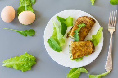 Beyaz bir tabakta yeşil ve roka ile iştah açıcı omlet..