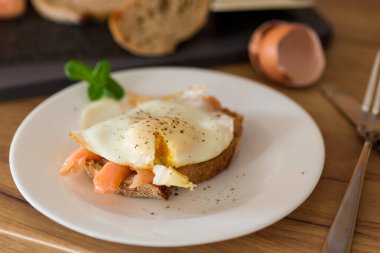 Hafif tuzlu kırmızı balıklı bir dilim ekmek ve kahvaltıda pişmiş yumurta..