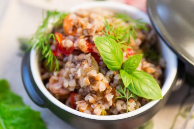 Tahta bir masada seramik kasede sebzeli haşlanmış karabuğday..