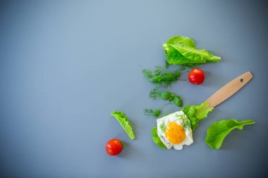 Sağlıklı yiyecek, yumurta ve salata spatulada, gri arka planda..