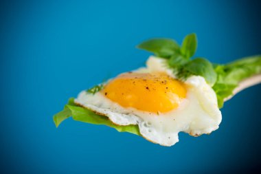 Sağlıklı yiyecek, yumurta ve marullu spatulaya yakın çekim. Mavi bir arkaplanda.