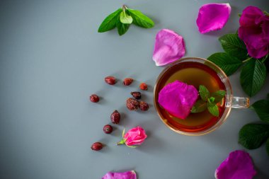 Şeffaf bir fincan ve çaydanlıkta ev yapımı gül suyu ve nane çayı..