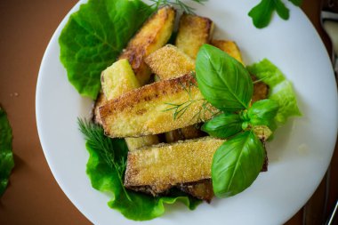 Kahverengi arka planda salata yeşili kızarmış kabak dilimleri..