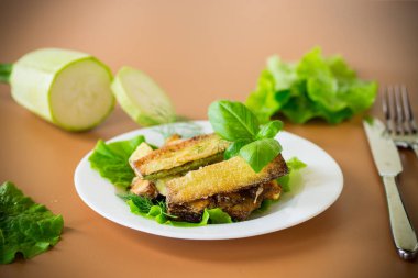 Kahverengi arka planda salata yeşili kızarmış kabak dilimleri..