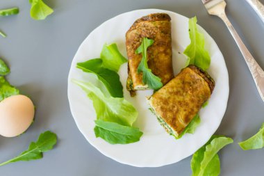 Beyaz bir tabakta yeşil ve roka ile iştah açıcı omlet..