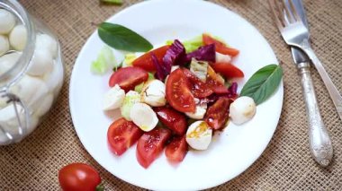 Mozzarella soslu salata ve ahşap bir masada domates.