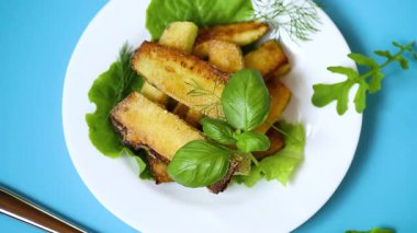 Kızarmış kabak dilimleri ve mavi arka planda salata yeşili..