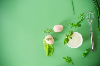 Yeşil arka planda bir kasede otlu ev yapımı yumurta mayonezi..
