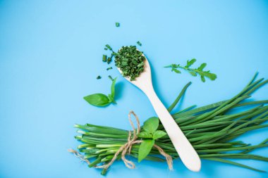 Kurumuş bitkilerin ve mavi arka planda taze yeşil soğanların üst görüntüsü.