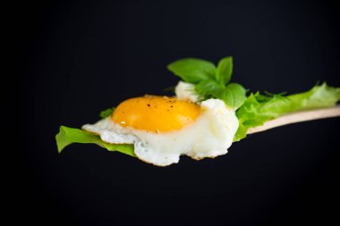 Siyah arka planda ahşap bir spatulada sahanda yumurta..