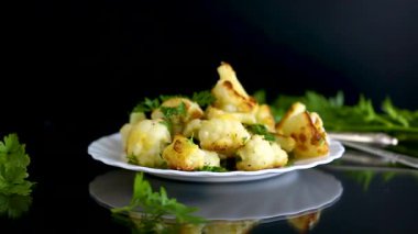 Siyah arka planda baharat ve otlarla kızartılmış karnabahar..