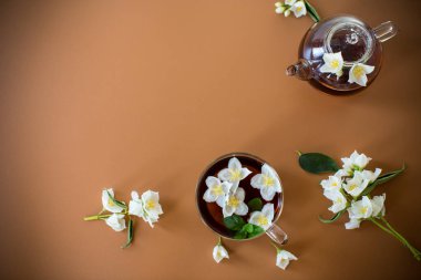 Kahverengi arka planda yasemin çiçekleri olan taze demlenmiş çay..