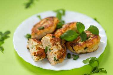 Yeşil arka planda izole edilmiş bir tabakta ev yapımı tavuk pirzolası..