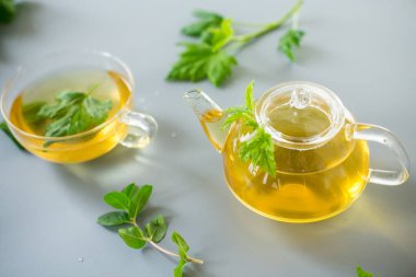 Cam çaydanlıkta çay ve fincanda frenk üzümü ve nane yaprağı..