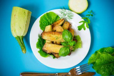 Mavi arka planda beyaz tabakta ev yapımı kızarmış kabak..