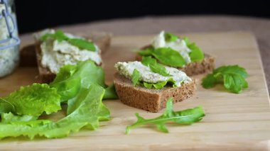 Peynirli çavdar ekmeği dilimi ve masada yeşillikler..