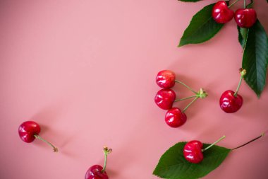 Yukarıdan pembe arka planda olgun kırmızı kirazlar.