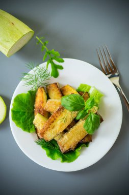 Beyaz bir tabakta gri arka planda ev yapımı kızarmış kabak..