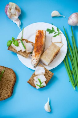 Domuz yağı ve soğanlı siyah ekmek - üst görünüm, mavi arka planda izole.