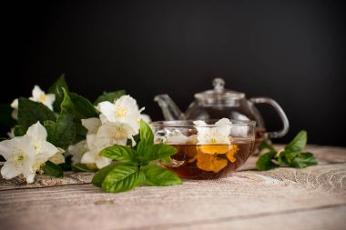 Yasemin çiçekli mis kokulu çay, siyah arka planda cam bir fincanda..