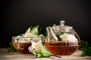 Yasemin çiçekleri ve çay siyah arka planda bir fincanda.