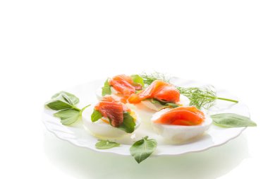 Beyaz bir arka planda balık dilimleri ile yumurtaların soğuk şenlikli aperatifi..