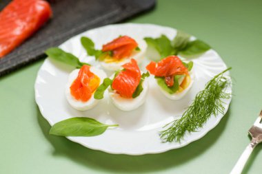 Yeşil arka planda somon, yumurta ve dereotuyla nefis bir meze..