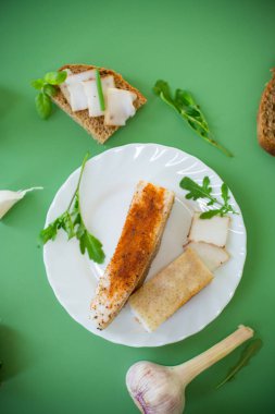 Yeşil zemin üzerinde domuz yağı ve yeşillik bulunan geleneksel Ukrayna yemeği.