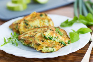 Ahşap bir masada yeşil soğanlı kızarmış kabaklı börek..