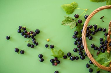 Yeşil arka planda bir sepetin yanında frenk üzümü var..