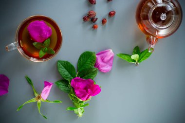 Bitki kökü ve nane çayı bir fincanda ve çaydanlık yukarıdan.