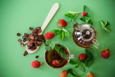 Yeşil arka planda şeffaf cam kaplı parlak çilek çayı..