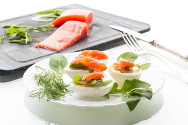 Kaynamış yumurta aperatifi ve beyaz arka planda dereotlu hafif tuzlanmış somon..