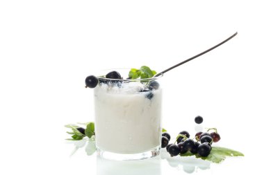 Beyaz arka planda böğürtlen ve kaşık ile sağlıklı mayalanmış süt ürünü.